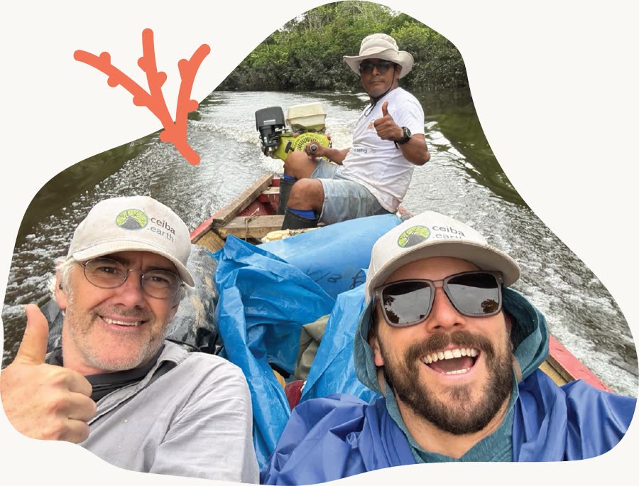 Three people in a motorised canoe on a jungle river in Peru, two of them wearing Ceiba Earth caps.