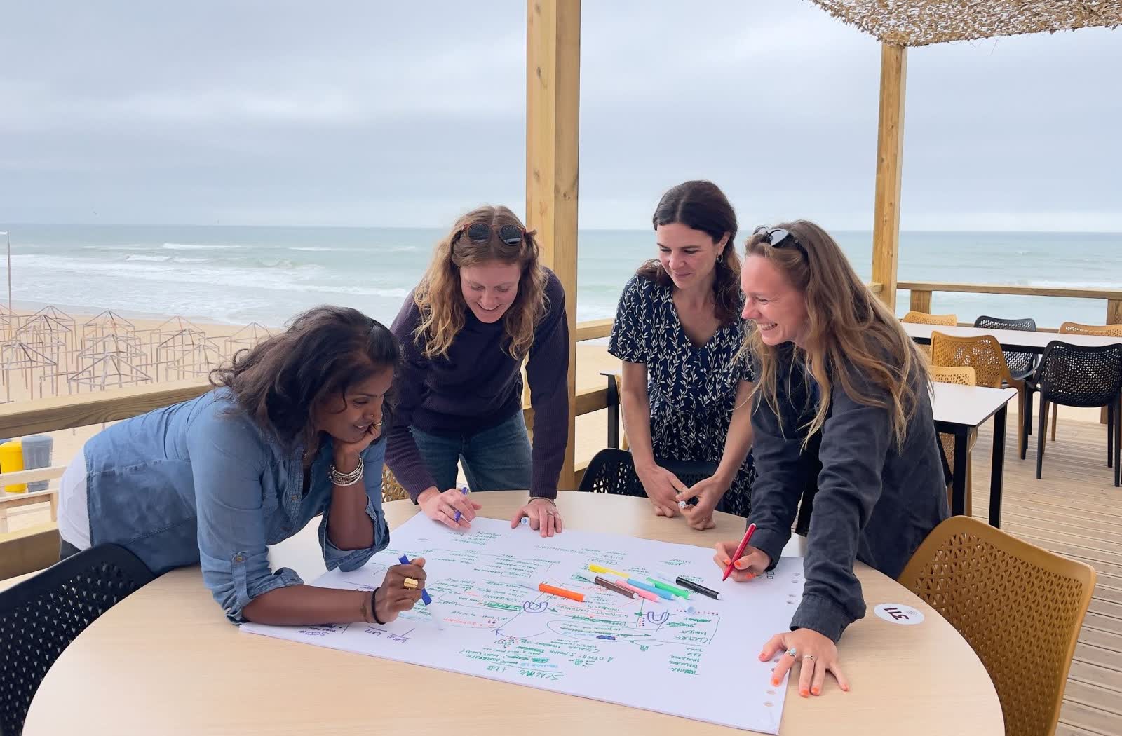 Four members of the founding coalition standing around a table, marking up a hand-drawn scaling map, with the ocean behind them.